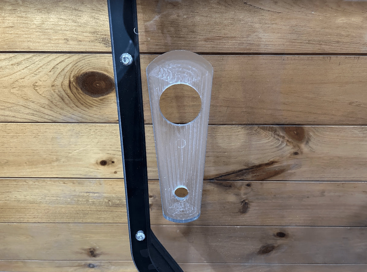 Close-up of John Deere P Series windshield frame left side showing clear polycarbonate latch and frame bolts