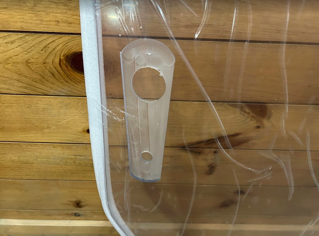 Close-up of John Deere P Series windshield hinge tab with mounting pin holes on the left frame