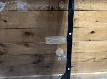 Close-up of tinted John Deere P Series windshield frame right side latch mechanism with catch bracket