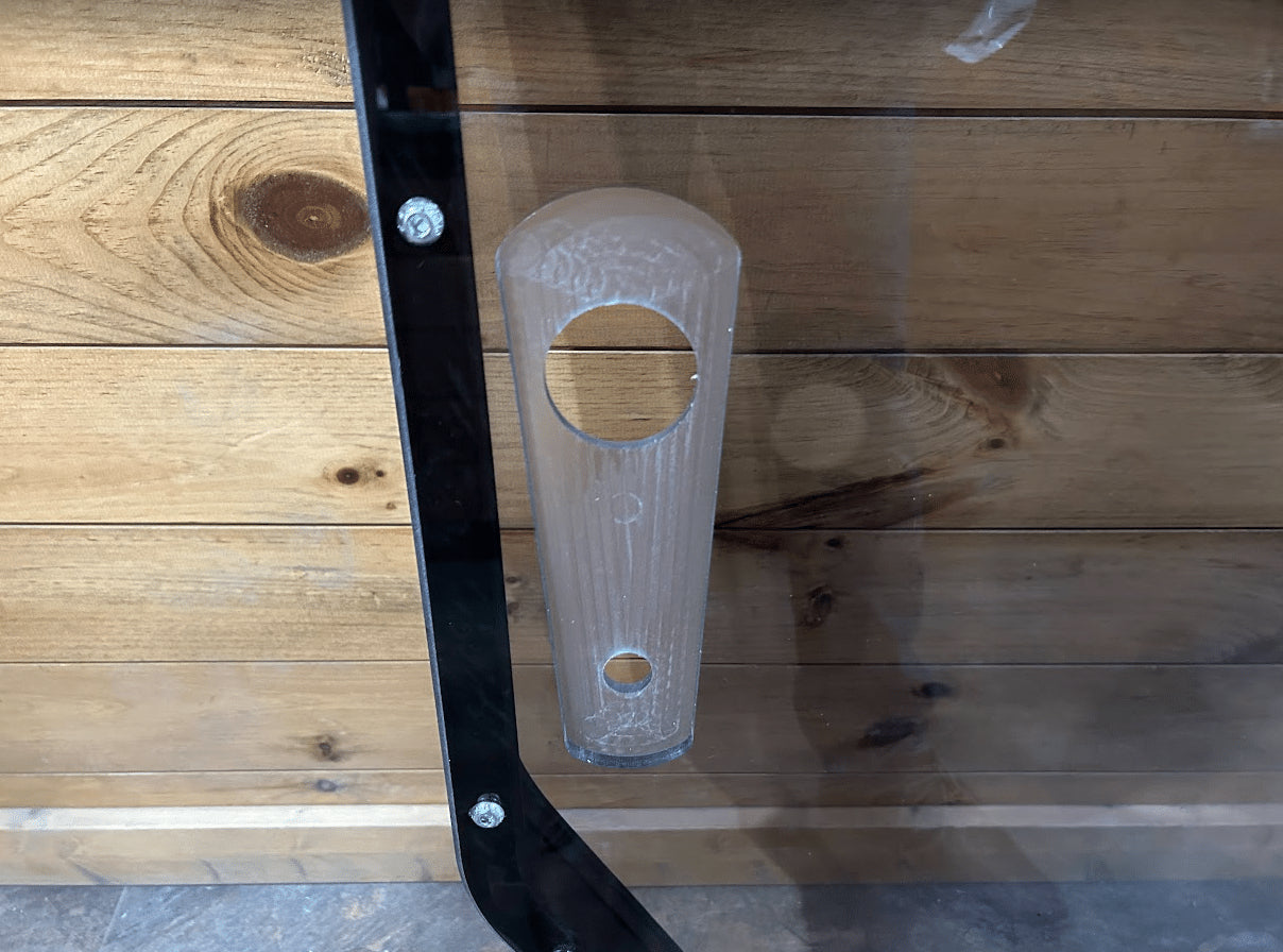 Close-up of tinted John Deere P Series windshield frame left side showing clear polycarbonate pull latch handle