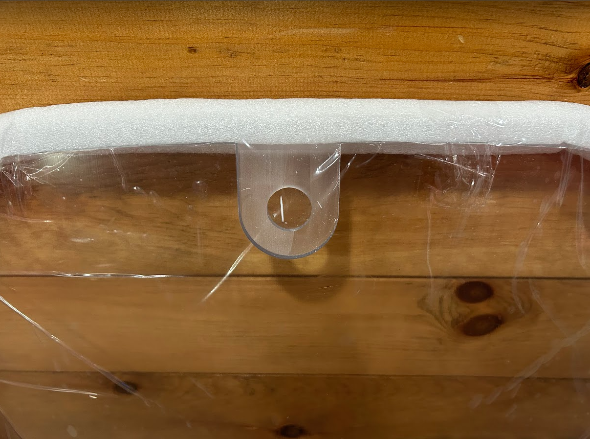 John Deere P Series windshield top edge showing white foam padding and hinge bracket with pin hole