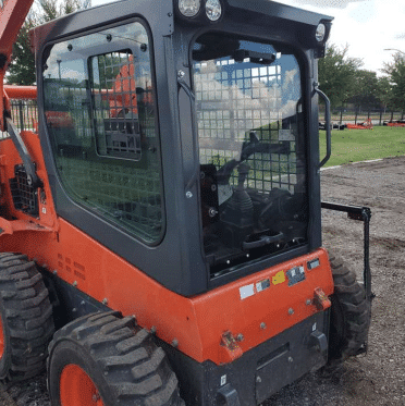 Kubota SSV skid steer shown from the front-left at a job site with polycarbonate windshield installed