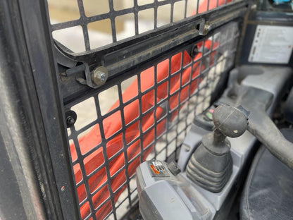 Inside view of Kubota SVL cab showing side window frame with retaining bars and joystick control visible