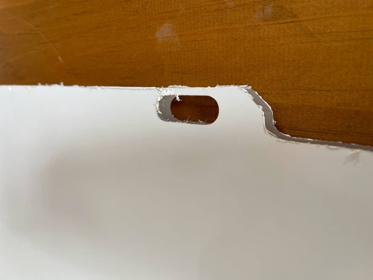 Close-up of oval bolt slot cutout in Kubota SVL polycarbonate side window panel for mounting hardware