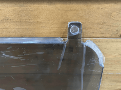 Close-up of top corner mounting tab and round hole on Kubota SVL clear polycarbonate side window panel
