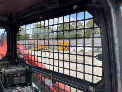 View from inside Kubota SVL cab looking out through side window opening with metal grill frame