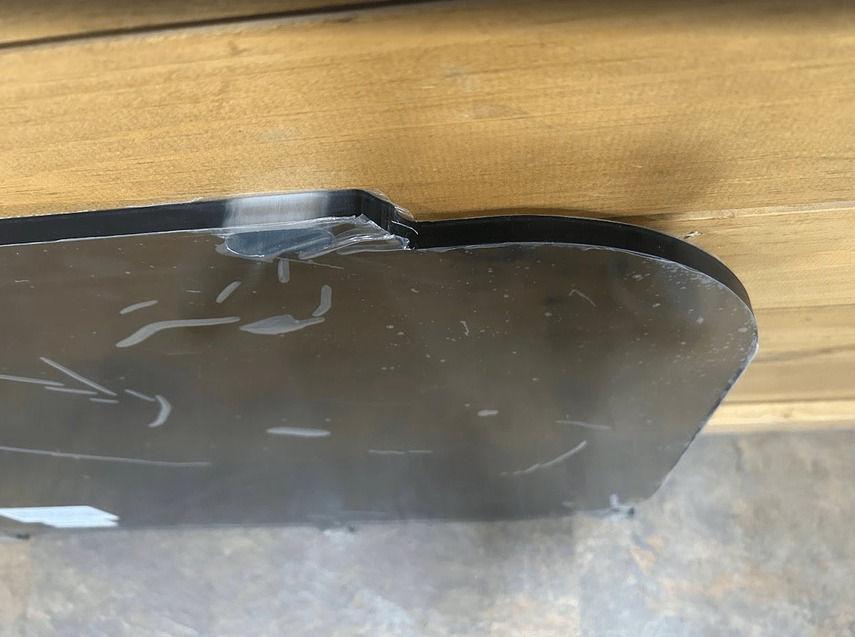 Close-up of curved corner edge on Kubota SVL tinted polycarbonate side window panel showing black frame profile