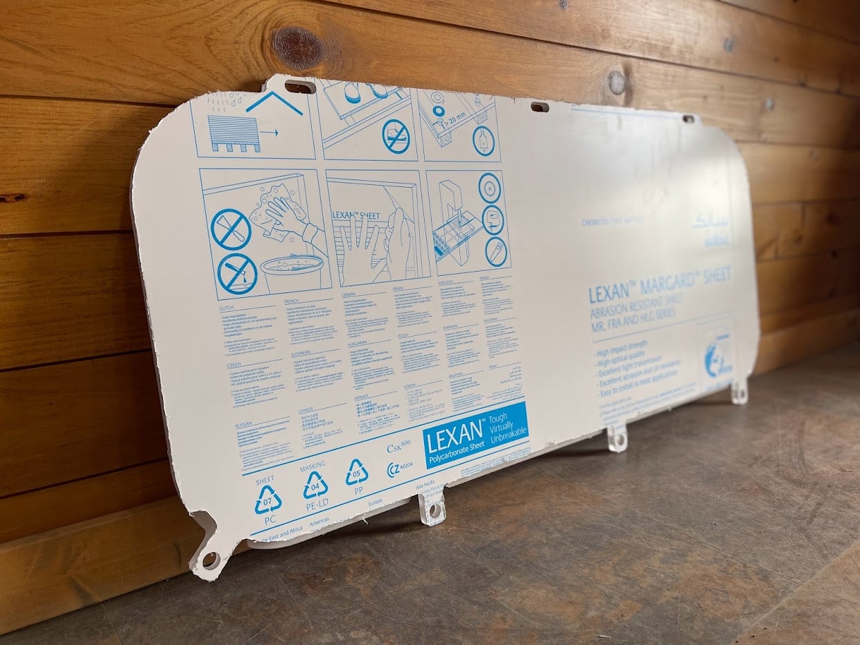 Kubota SVL upper polycarbonate side window panel showing Lexan Margard protective film on back side