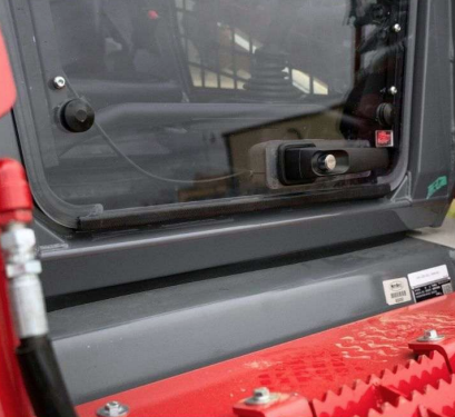 Close-up of Takeuchi TL8R2 polycarbonate windshield edge and door frame with fastening hardware