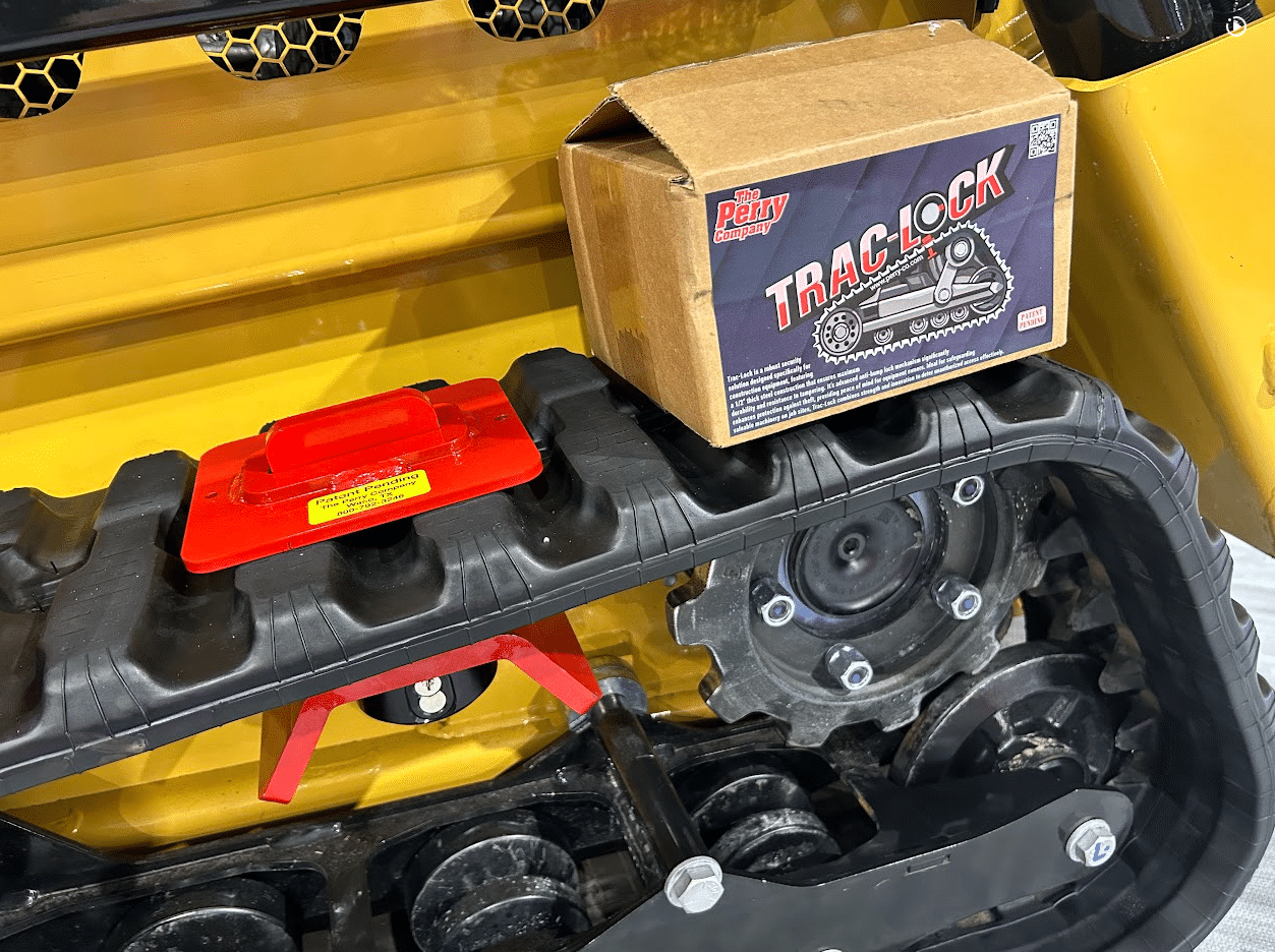 Trac-Lock anti-theft device and Perry Company retail box resting on the rubber track of a mini skid steer