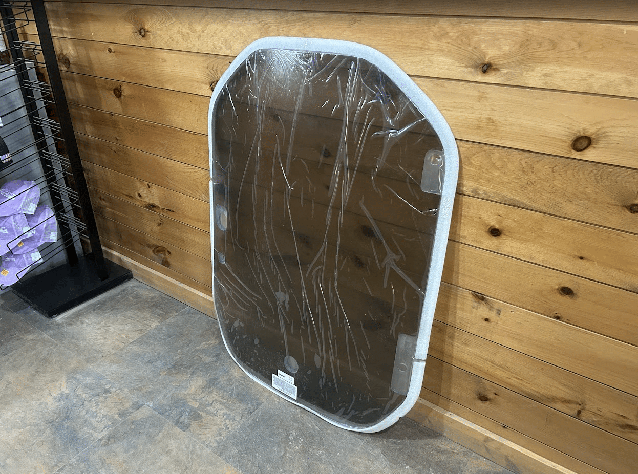 Wacker Neuson ST/SW tinted polycarbonate windshield leaning against a wall showing the angle and rubber frame