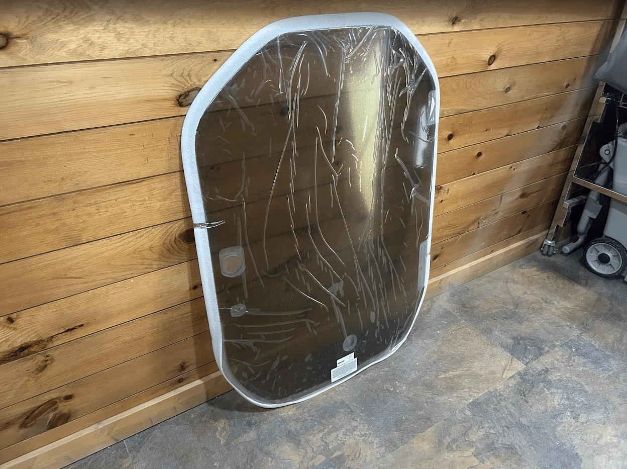 Wacker Neuson ST/SW tinted polycarbonate windshield leaning upright against a wood wall, side view