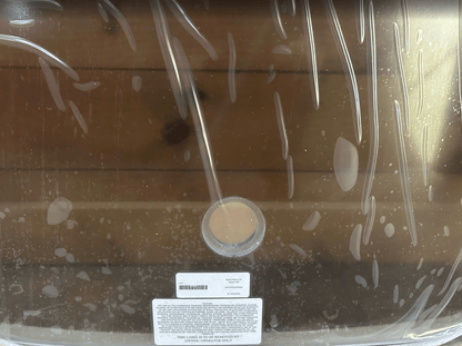 Close-up of the bottom of a Wacker Neuson ST/SW tinted windshield showing the wiper motor hole cutout and product label